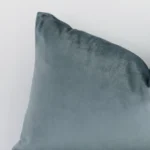 Close up image of top corner of this solid-coloured sage green cushion. This shows the velvet fabric and rectangular shape up close.