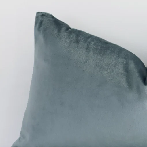 Close up image of top corner of this solid-coloured sage green cushion. This shows the velvet fabric and rectangular shape up close.