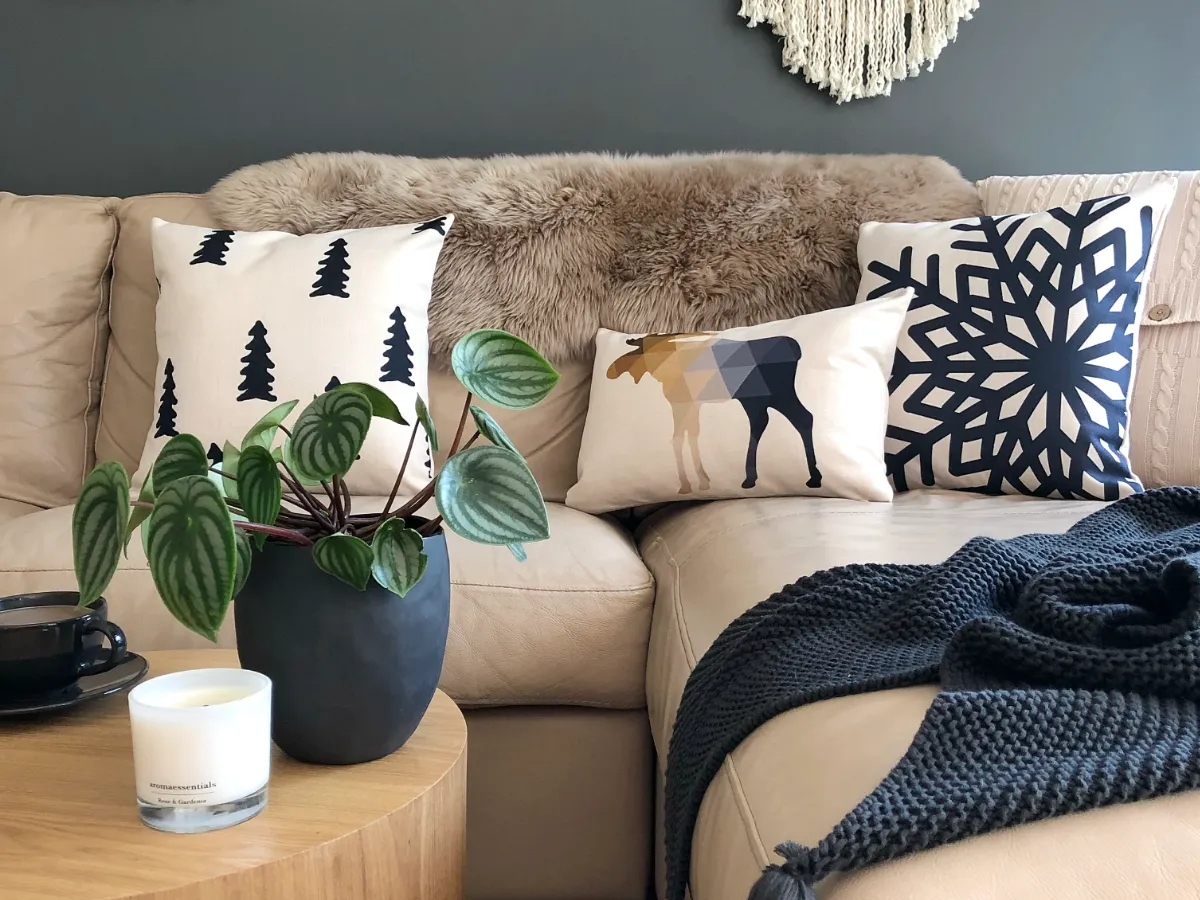 Scandi cushion patterns resting on a sofa with dark colours.