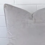 A zoomed in photo of the corner of a silver grey cushion that has velvet fabric and a large size.