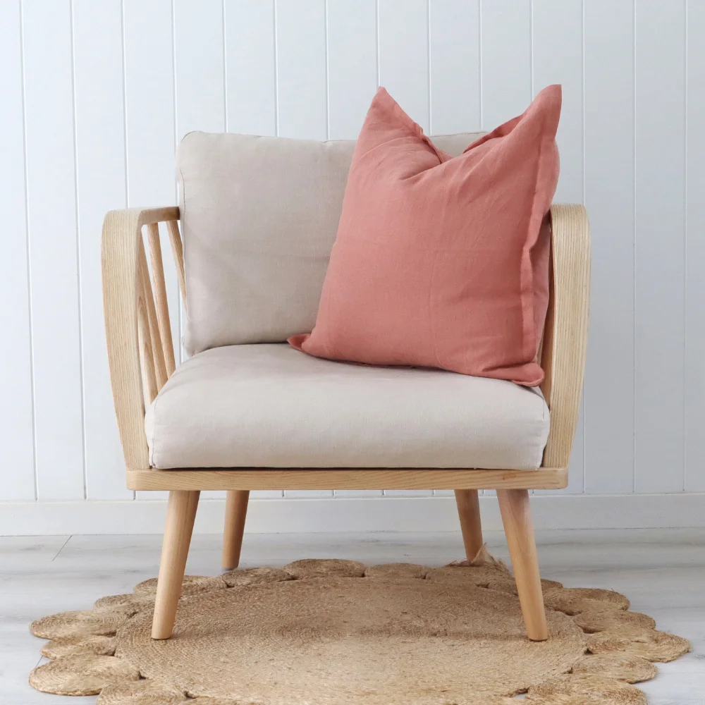 A simple elegant chair with a pink cushion placed to the side.