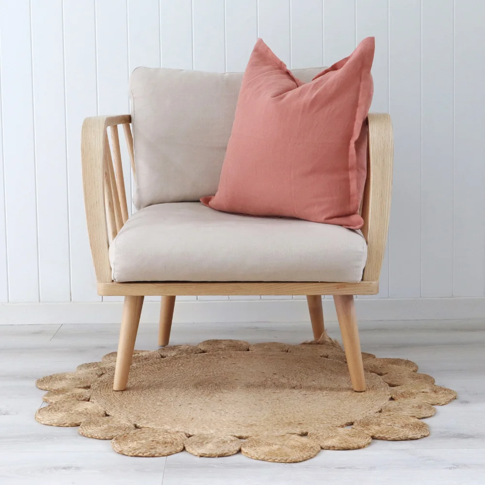 A single chair sits on a woven rug and has peach cushions styled on it.