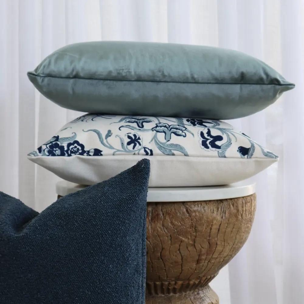 A small arrangement of designs centred near a round stool which has a velvet cushion on top.