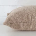 A large beige cushion cover laying flat. This viewpoint highlights the boucle fabric from a side position.