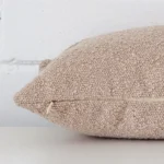 A beige cushion positioned on its back panel. The shot shows a lateral view of the boucle fabric and its rectangle size.