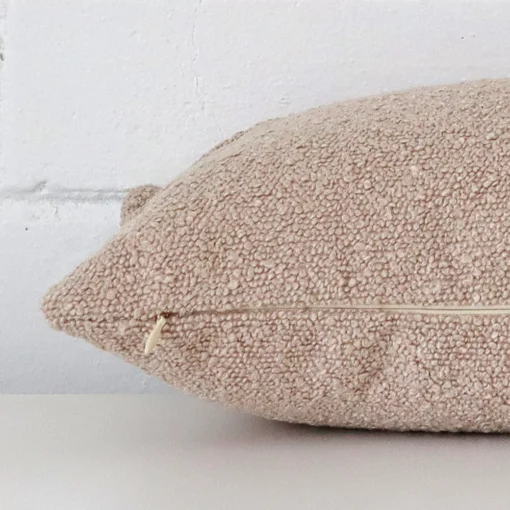 A beige cushion positioned on its back panel. The shot shows a lateral view of the boucle fabric and its rectangle size.