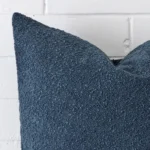 A blue boucle cushion cover’s corner is shown in more detail. It has large dimensions.