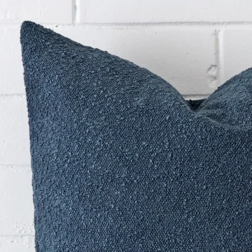 A blue boucle cushion cover’s corner is shown in more detail. It has large dimensions.