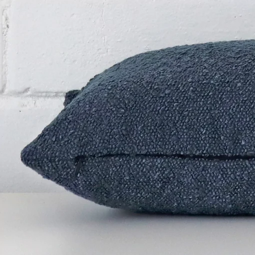 A side shot of a boucle cushion cover. The angle shows the edge of the rectangle shape and the blue tone.