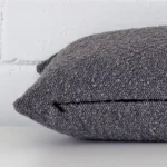 A boucle dark grey cushion cover shown laying on its side. It has rectangle size.