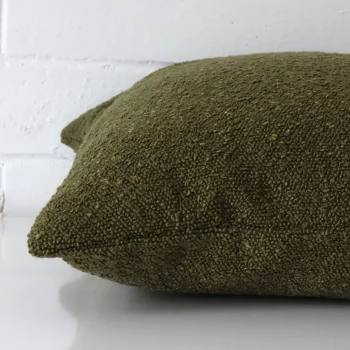 The seams of this boucle large cushion cover in olive green are shown.