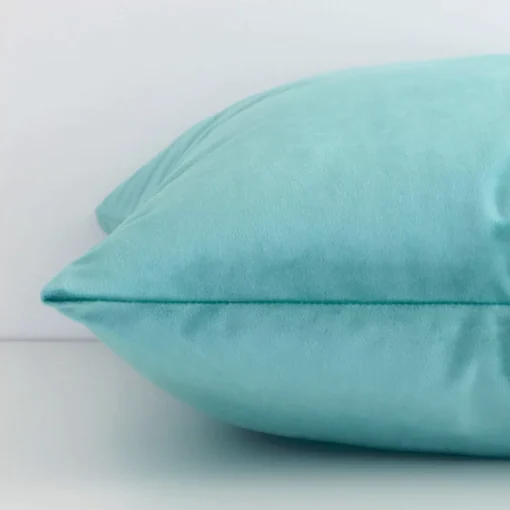 Side angle of spearmint solid-coloured cushion cover that has velvet fabric and a square shape.