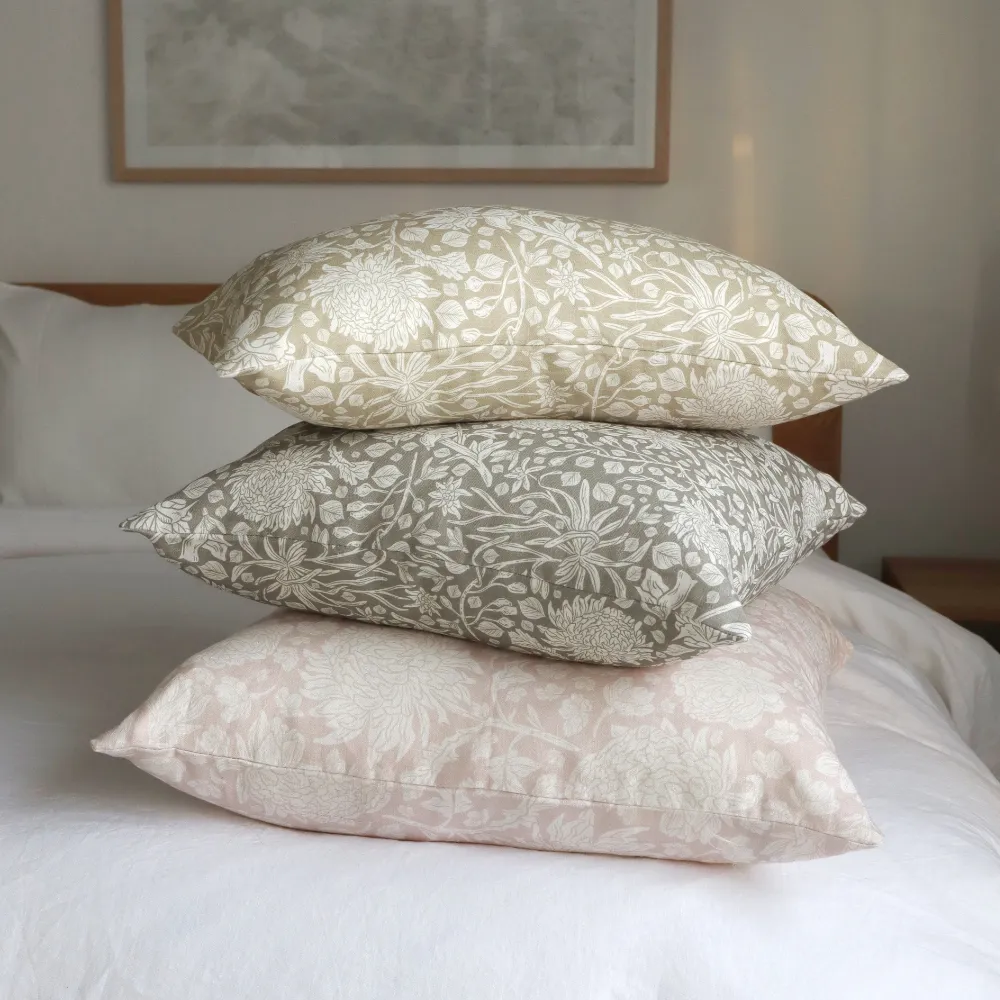 A stack of floral cushions are arranged on a bed.