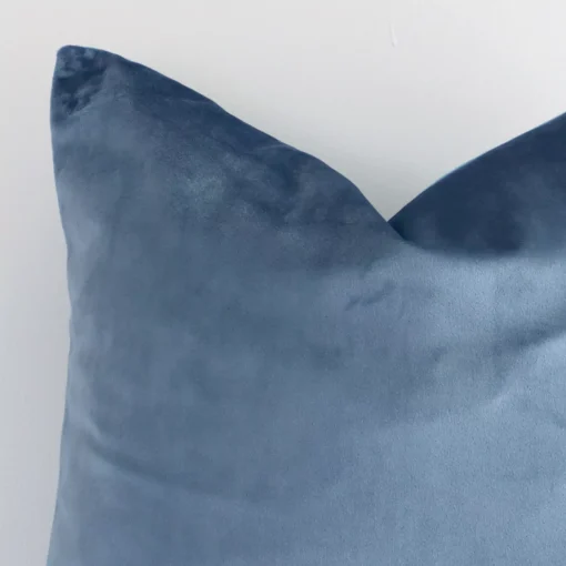 Extreme close up of a square stone blue cushion. The solid-coloured style and velvet fabric are shown with a much higher degree of detail.