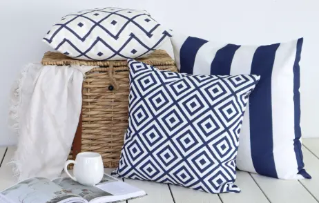 Stylish blue outdoor cushions arranged near a picnic basket with a cup and magazine.