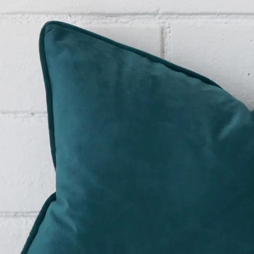 A teal velvet cushion cover’s corner is shown in more detail. It has a rectangle design.