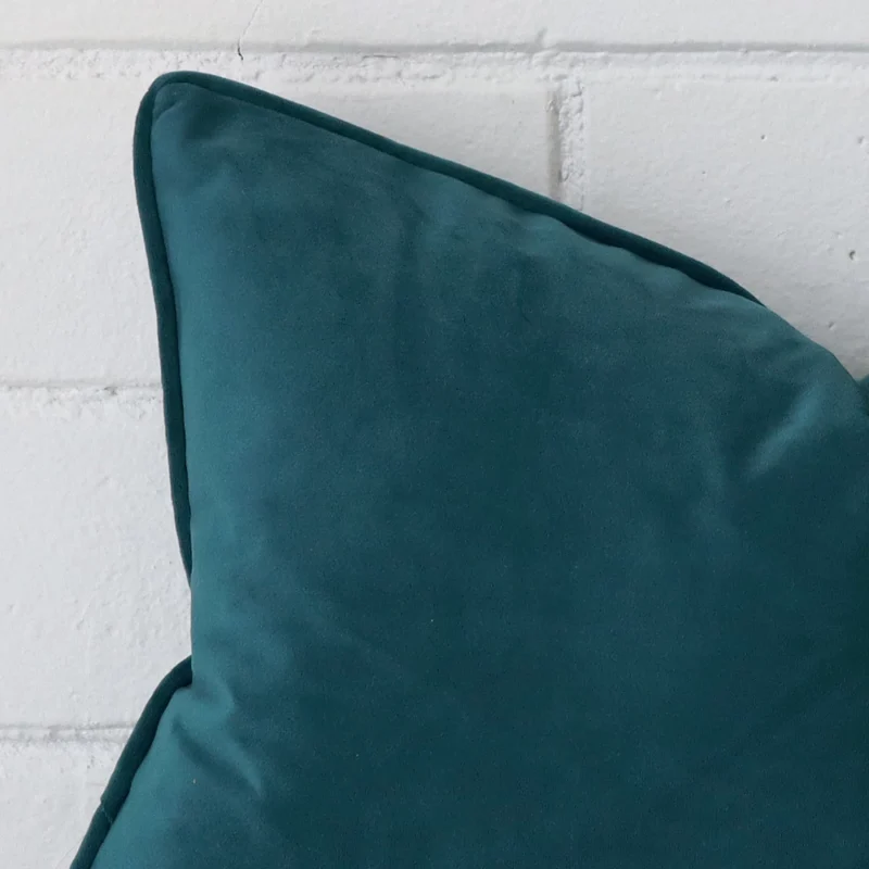 A teal velvet cushion cover’s corner is shown in more detail. It has a rectangle design.