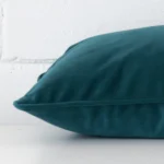 Side angle of teal cushion cover that has velvet fabric and a rectangle size.