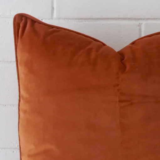 A zoomed view of this velvet terracotta cushion’s corner that has a large size.