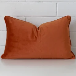 A hero shot of a rectangle cushion cover. It is made from a deluxe velvet fabric and features a terracotta colour.