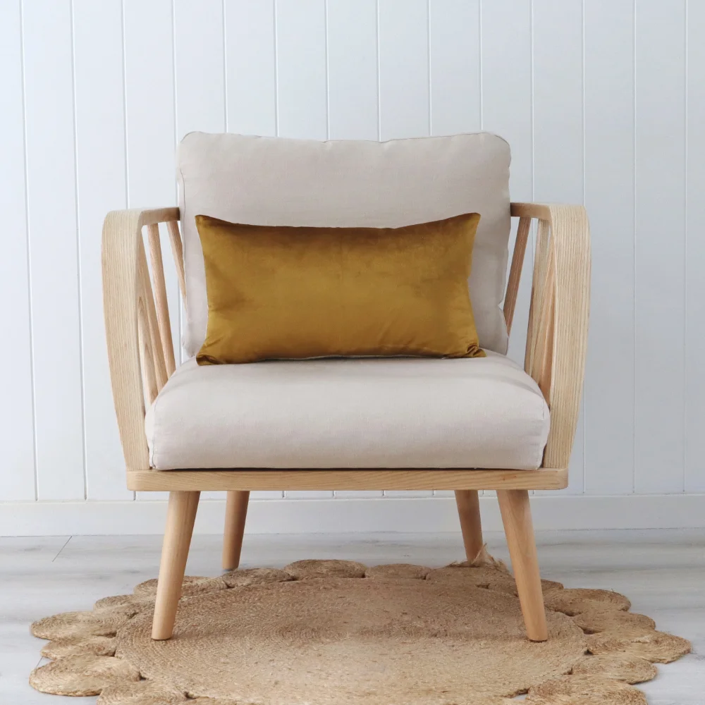 A timber chair faces forward with a gold cushion in its middle.