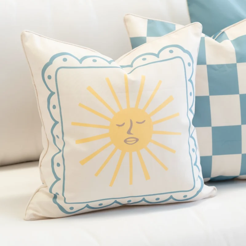 Tropica cushion with sun face design and blue scalloped border.
