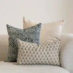 A set of 3 designer covers from the Vada set in the corner of a natural-coloured sofa.