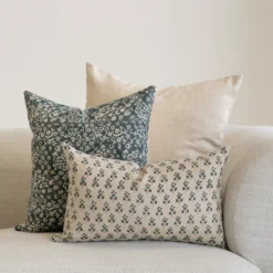 A set of 3 designer covers from the Vada set in the corner of a natural-coloured sofa.
