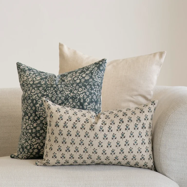 A set of 3 designer covers from the Vada set in the corner of a natural-coloured sofa.