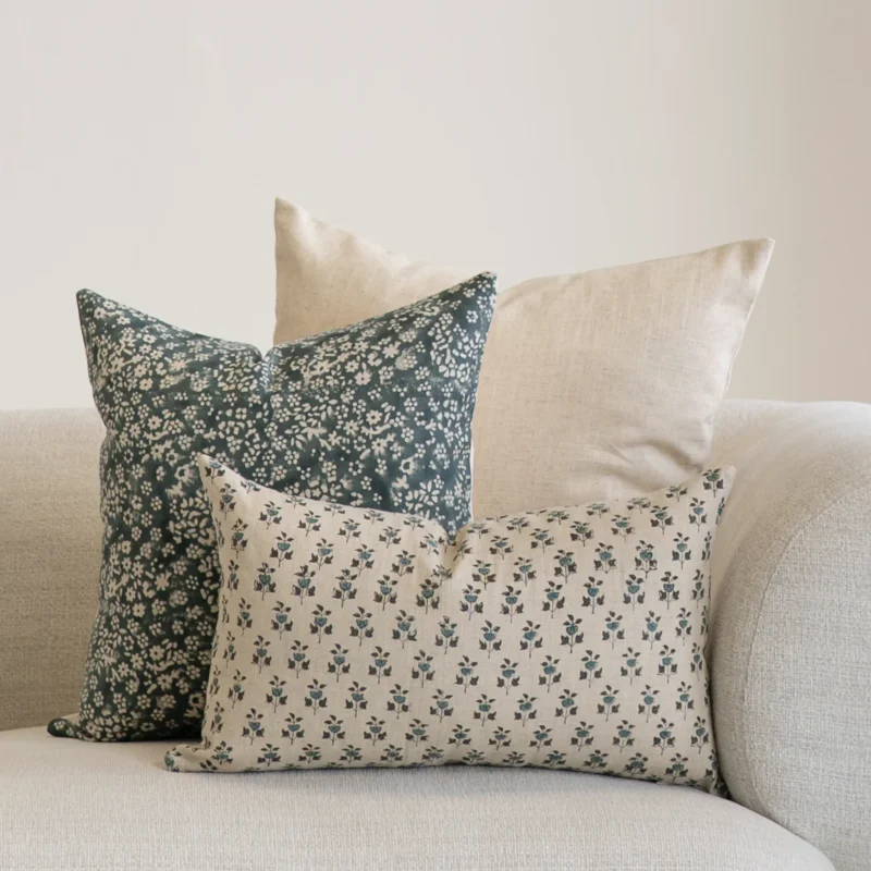 A set of 3 designer covers from the Vada set in the corner of a natural-coloured sofa.