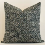 Dark moss green linen cushion cover features prominently against a white wall. It is a large design and has a floral decorative finish.