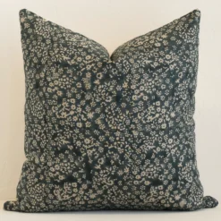 Dark moss green linen cushion cover features prominently against a white wall. It is a large design and has a floral decorative finish.