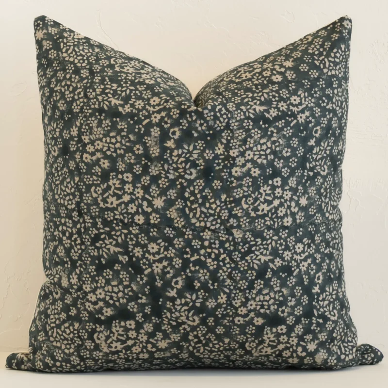 Dark moss green linen cushion cover features prominently against a white wall. It is a large design and has a floral decorative finish.