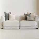 A living room with a natural-coloured sofa showcasing 5 designer Vada cushion covers.