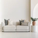 A living room featuring a natural-coloured sofa adorned with a neatly arranged set of 5 Vada designer cushion covers.