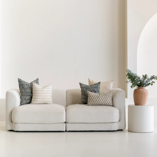 A living room featuring a natural-coloured sofa adorned with a neatly arranged set of 5 Vada designer cushion covers.