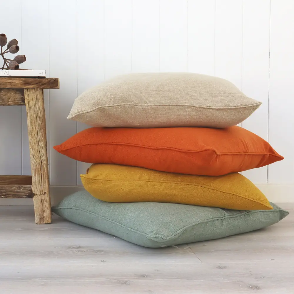A weathered table sits next to some block coloured polyester cushions.