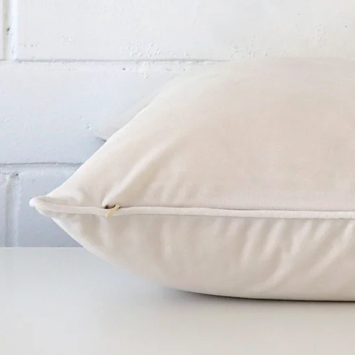 A white cushion cover is laid flat. This angle shows the side of the velvet fabric and its large shape.