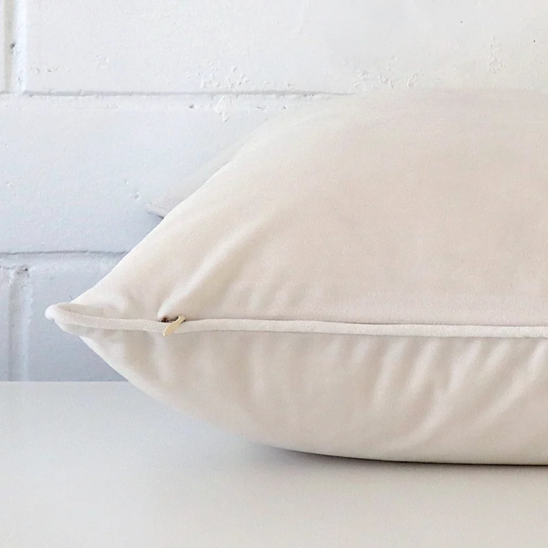 A white cushion cover is laid flat. This angle shows the side of the velvet fabric and its large shape.
