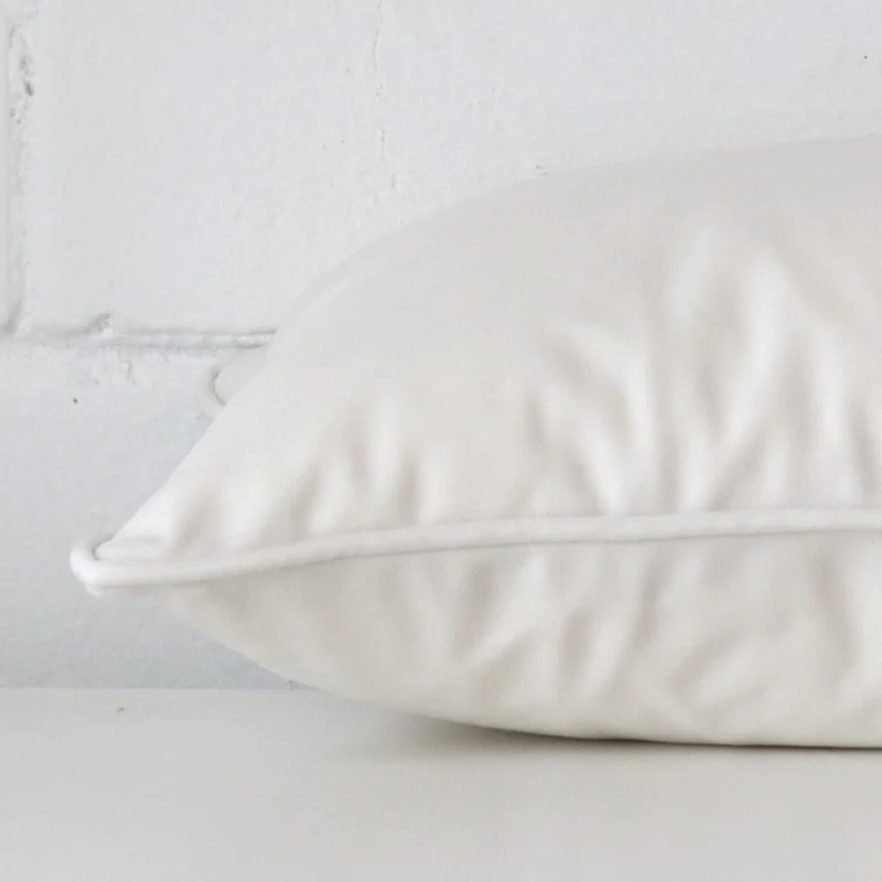 Horizontal edge of rectangle cushion cover is shown. The velvet fabric and white tone can be seen from this side view.
