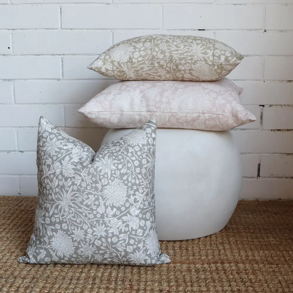 A white wall acts as a backdrop to a stack arrangement of boho cushions.