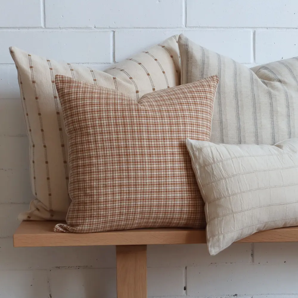 A wooden bench seat hosts a group of Thai woven designer cushions.