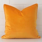 A graceful large yellow cushion made from a durable velvet fabric.