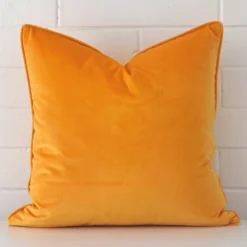 A graceful large yellow cushion made from a durable velvet fabric.