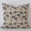 Here a designer cushion is shown styled against a white wall. It has a large size and features a floral style.