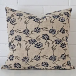 Here a designer cushion is shown styled against a white wall. It has a large size and features a floral style.