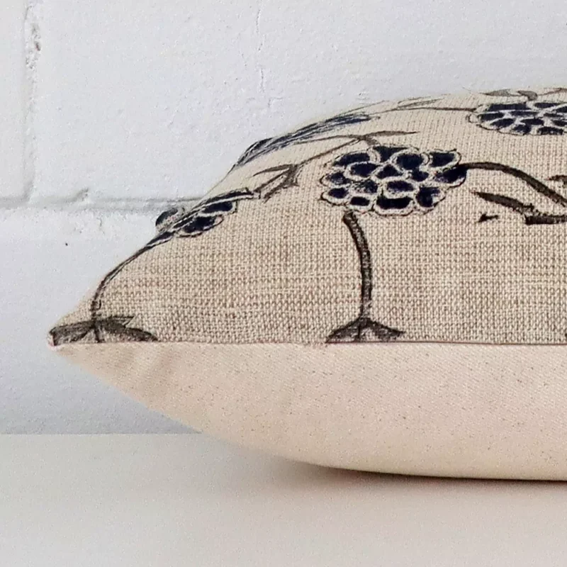 A large cushion cover laying flat. This viewpoint highlights the floral style and designer fabric from a side position.