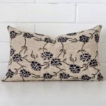 A lovely rectangle cushion cover arranged in front of a white wall. The floral style complements the designer material.